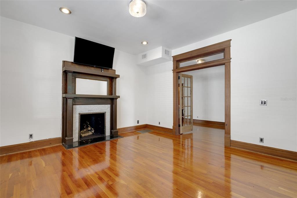 A room with hardwood floors, a fireplace with a wooden mantel, and a doorway — 716 E LIME STREET, LAKELAND, FL