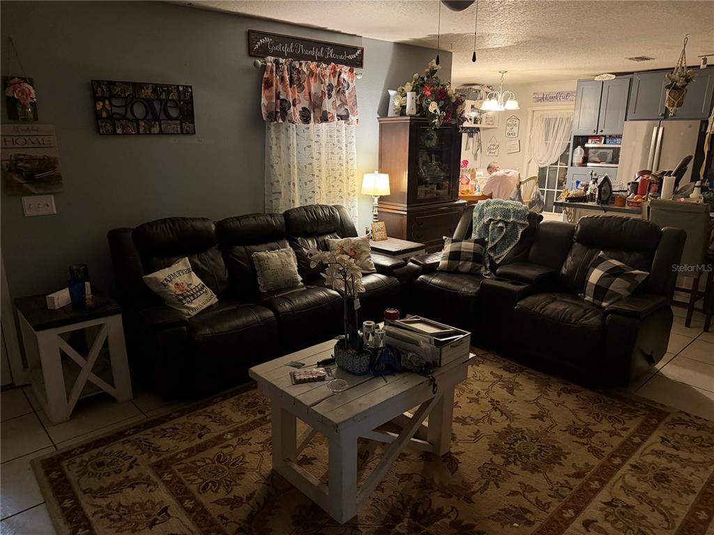 A living room features dark leather reclining sofas, a white coffee table, and a rug — 92 WHEATFIELD DRIVE, PALM COAST, FL