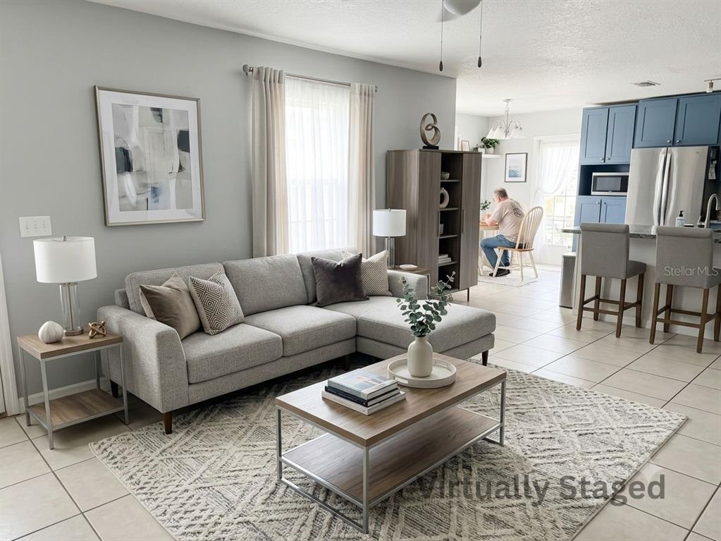 A living room with a gray sectional sofa, coffee table, and an open kitchen area — 92 WHEATFIELD DRIVE, PALM COAST, FL