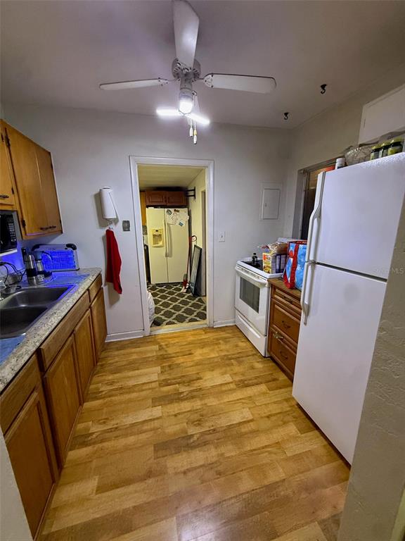 A kitchen features wood cabinets, a white refrigerator, a ceiling fan, and light wood flooring — 21234 GLADIS AVENUE, PORT CHARLOTTE, FL