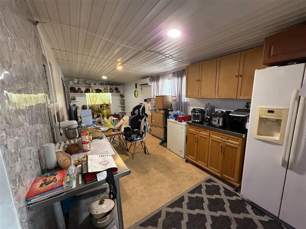 A kitchen with wooden cabinets, a white refrigerator, and a cluttered workspace area — 21234 GLADIS AVENUE, PORT CHARLOTTE, FL