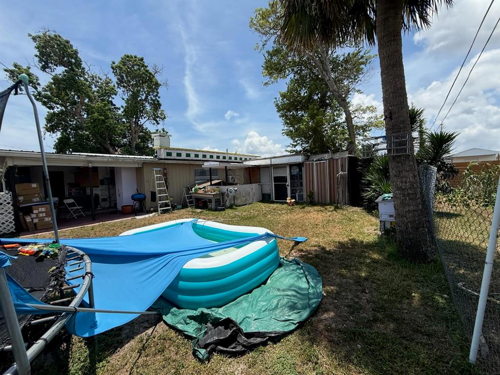 A backyard features an inflatable pool, a trampoline with a blue cover, and a house exterior — 21234 GLADIS AVENUE, PORT CHARLOTTE, FL