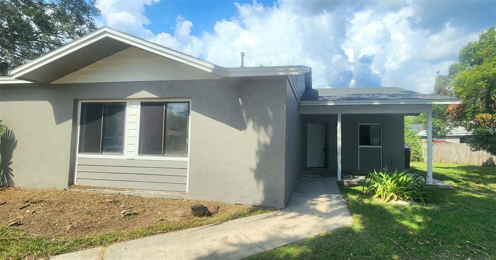 A gray single-story house with a covered entryway and a concrete walkway in the yard — 615 SW 3RD STREET, GAINESVILLE, FL