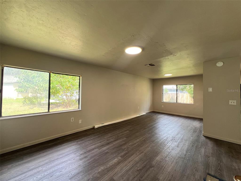 An empty room with light gray walls, dark wood-look flooring, and two windows — 615 SW 3RD STREET, GAINESVILLE, FL