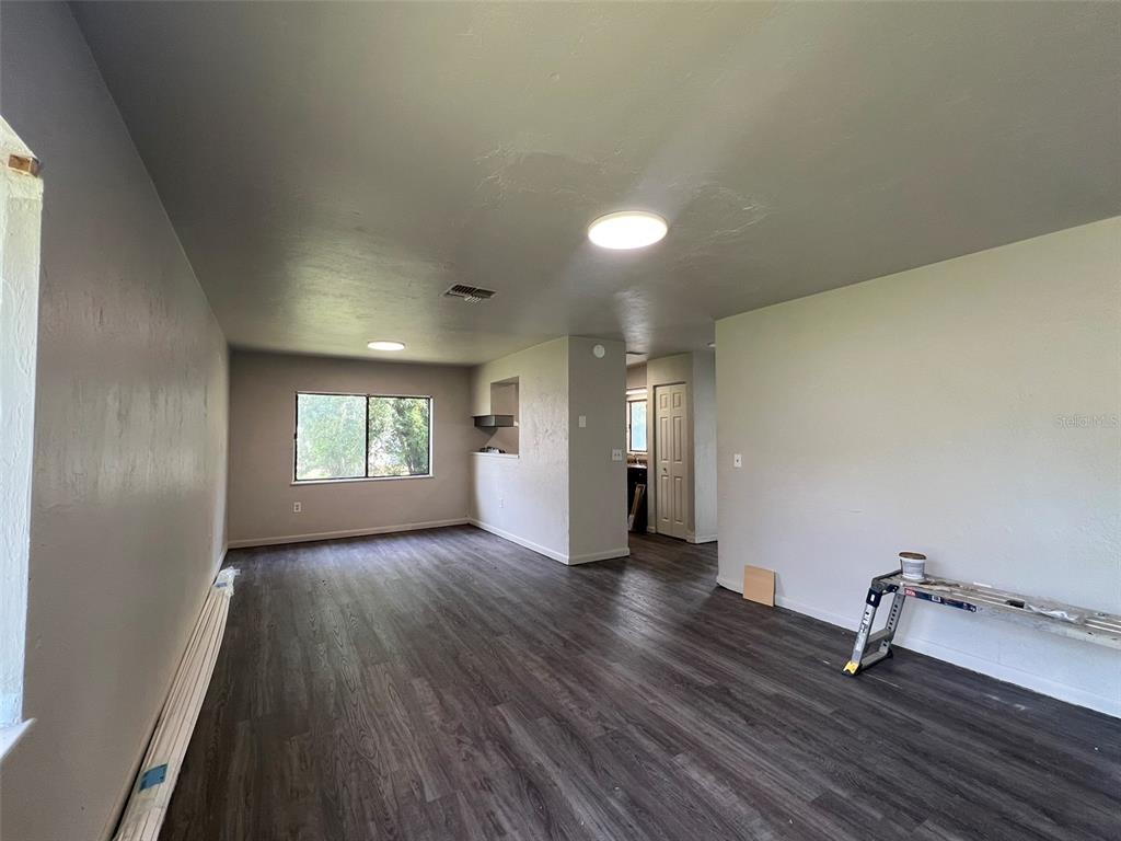 An empty room features gray walls, dark wood-look flooring, and two flush-mount ceiling lights — 615 SW 3RD STREET, GAINESVILLE, FL