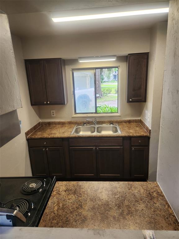 A kitchen features dark wood cabinets, brown laminate countertops, a double sink, and a window — 615 SW 3RD STREET, GAINESVILLE, FL