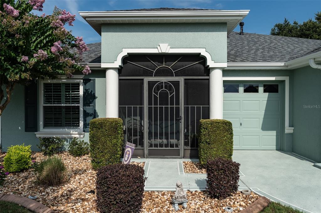 The exterior of a light green house features a screened entryway and a garage — 16364 SW 14TH COURT, OCALA, FL