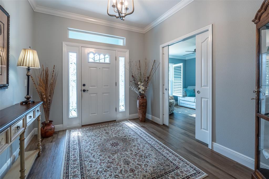 A foyer with wood-look flooring, a white front door, and a rug leads to a room — 16364 SW 14TH COURT, OCALA, FL