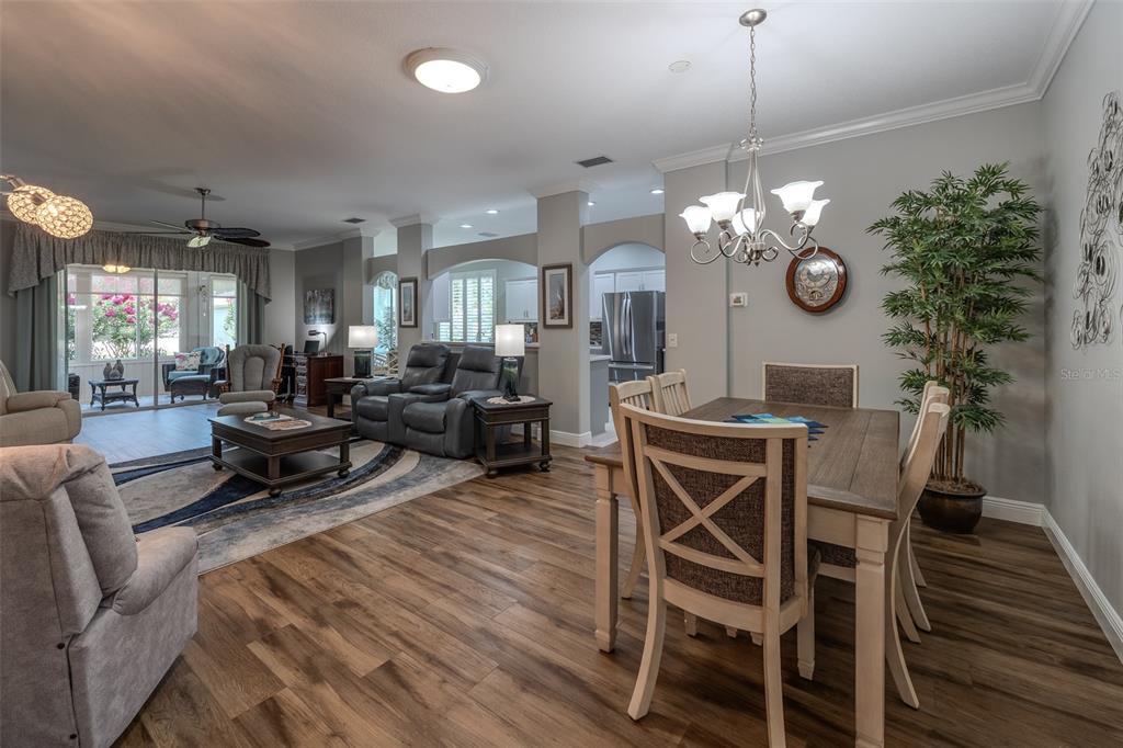An open-concept living and dining area features wood-look flooring, neutral walls, and a ceiling fan — 16364 SW 14TH COURT, OCALA, FL