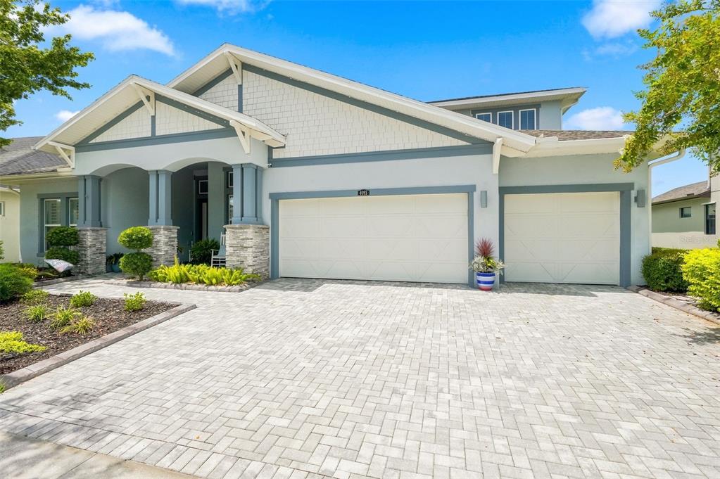 A light blue house with a three-car garage and a paved driveway under a blue sky — 4093 EPIC COVE, LAND O LAKES, FL