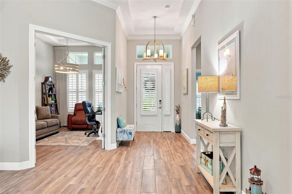 A bright entryway features wood-look flooring, a white front door, and an adjacent home office — 4093 EPIC COVE, LAND O LAKES, FL
