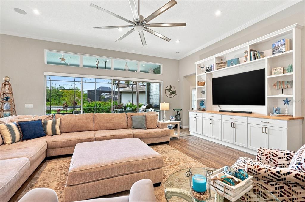 A living room features a large sectional sofa, a built-in media center, and a ceiling fan — 4093 EPIC COVE, LAND O LAKES, FL