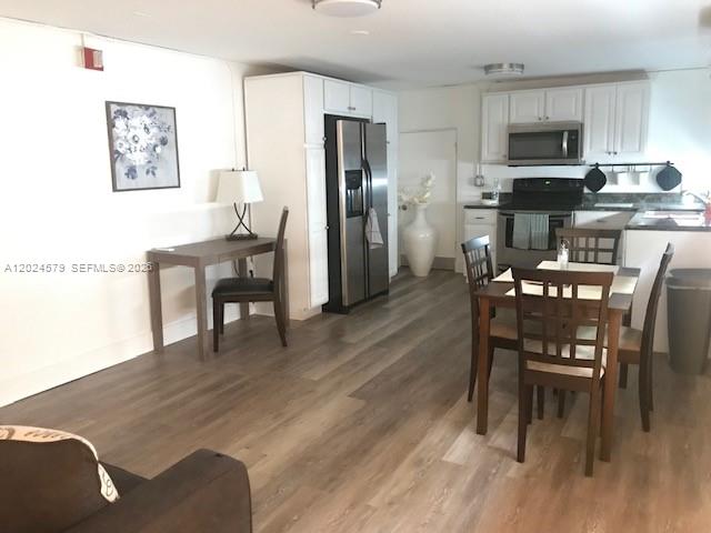 This open-concept kitchen and dining area features light wood-look flooring and white cabinetry — 923 SW 43 ave # 1, Miami FL 33134, MIAMI, FL
