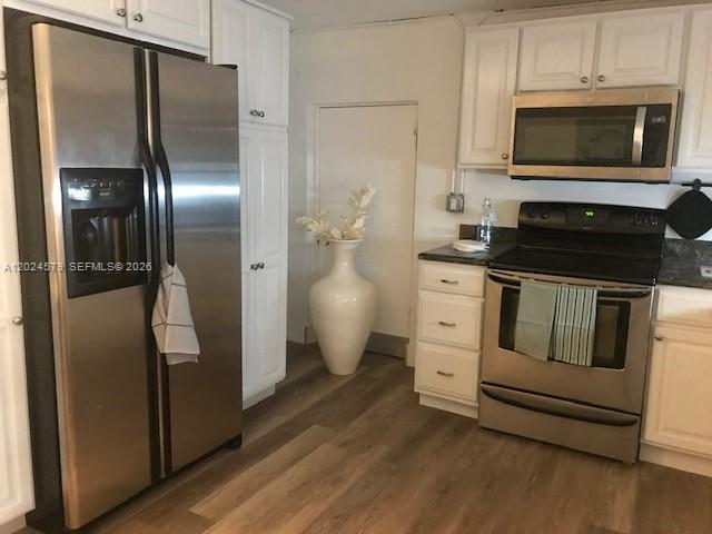 A kitchen features stainless steel appliances, white cabinets, and wood-look flooring — 923 SW 43 ave # 1, Miami FL 33134, MIAMI, FL