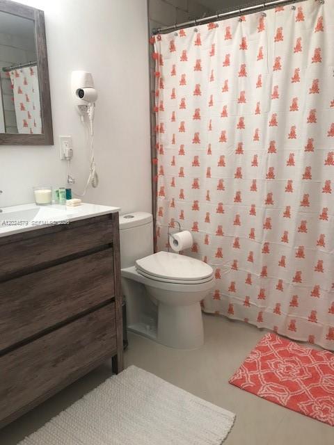 A bathroom features a wood-toned vanity, a white toilet, and a patterned orange shower curtain — 923 SW 43 ave # 1, Miami FL 33134, MIAMI, FL