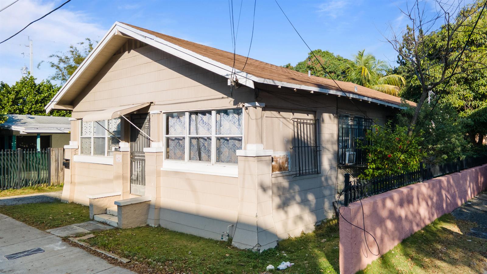 A tan, single-story house with a gabled roof, white trim, and a pink perimeter wall — 8111 NE 1st Avenue, Miami FL 33138, MIAMI, FL
