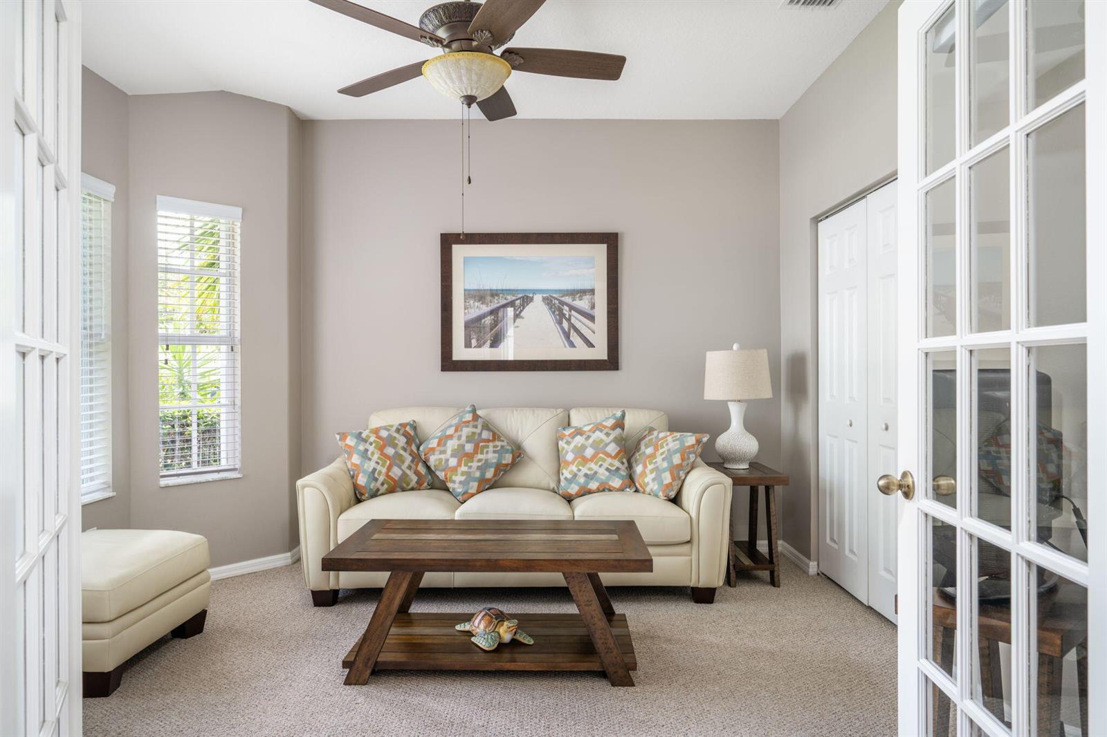 A small living room features a beige sofa, a wooden coffee table, and a ceiling fan — 1336 Shoreline Circle, Sebastian FL 32958, SEBASTIAN, FL