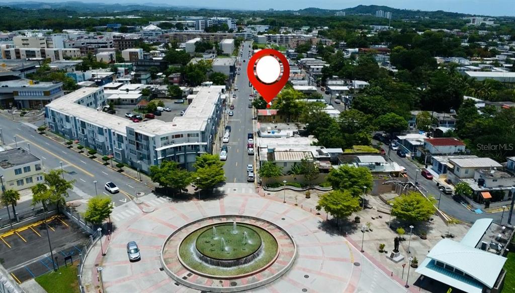 An aerial view shows a town square with a fountain and a marked commercial property — Bo. Pueblo C. PEDRO ARZUAGA, CAROLINA, PR
