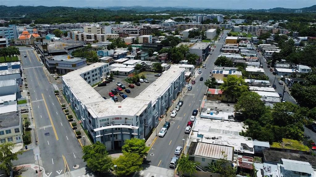 An aerial view shows a multi-story apartment building with a parking lot in a city — Bo. Pueblo C. PEDRO ARZUAGA, CAROLINA, PR