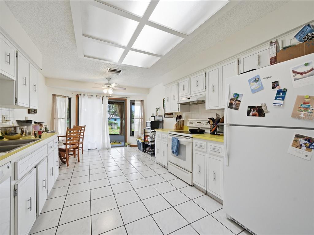 A kitchen with white cabinets, yellow countertops, tile flooring, and a large ceiling light fixture — 241 DARTMOUTH AVENUE, SPRING HILL, FL