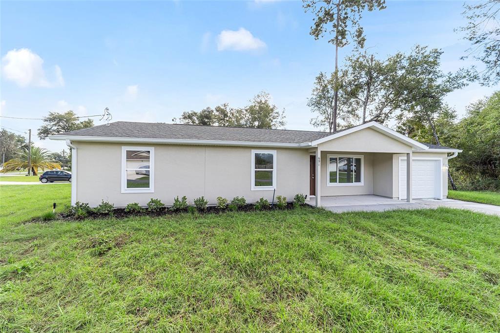 A single-story house with light-colored siding, a covered porch, and an attached garage — 23827 SW BEAVER DRIVE, DUNNELLON, FL