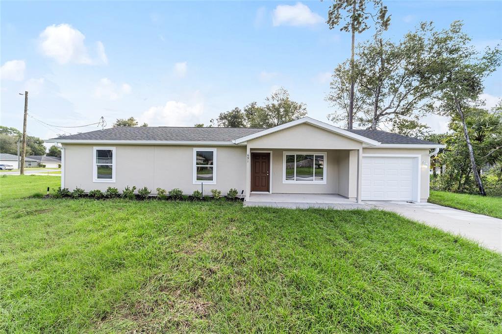 A single-story house with a beige exterior, a front porch, and an attached garage — 23827 SW BEAVER DRIVE, DUNNELLON, FL