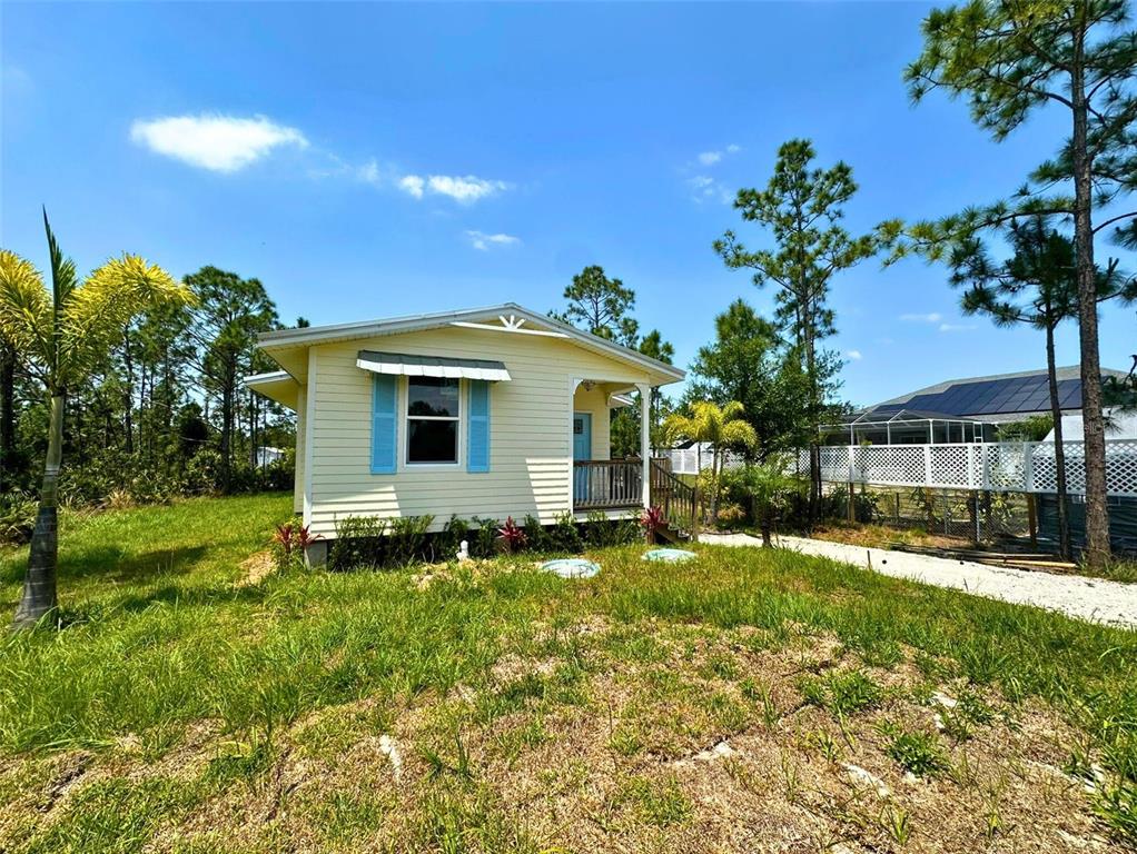 A small, light yellow house with blue shutters sits on a grassy lot — 8297 STRASSE BOULEVARD, PUNTA GORDA, FL