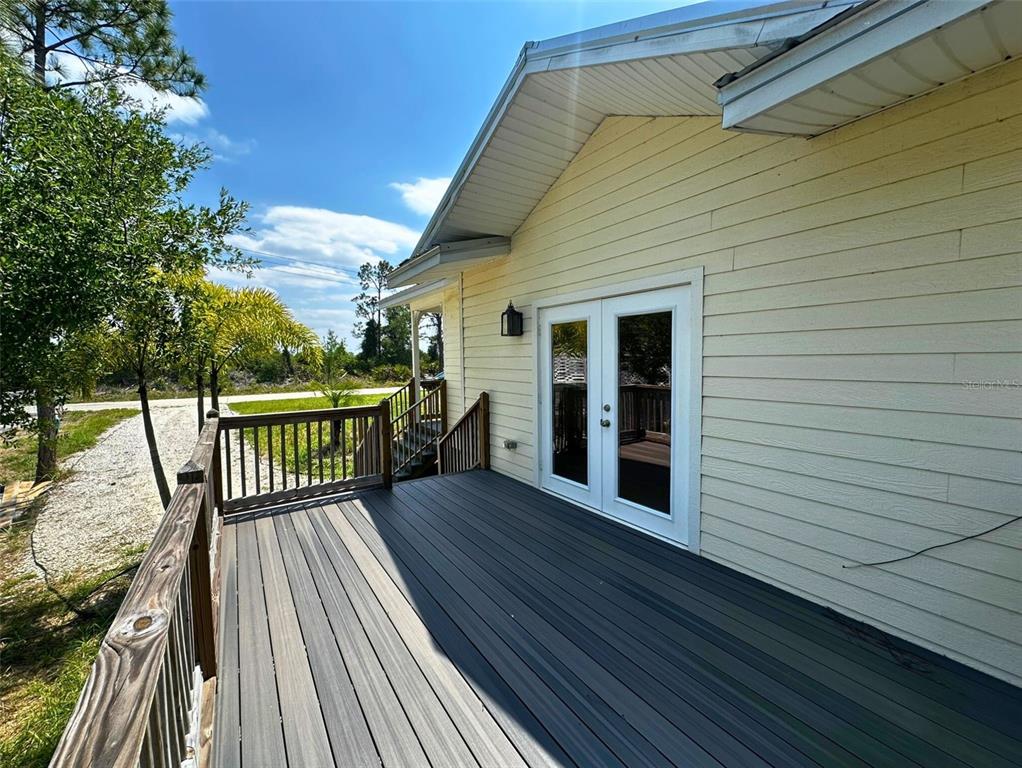 A wooden deck with railings extends from the side of a yellow house with French doors — 8297 STRASSE BOULEVARD, PUNTA GORDA, FL