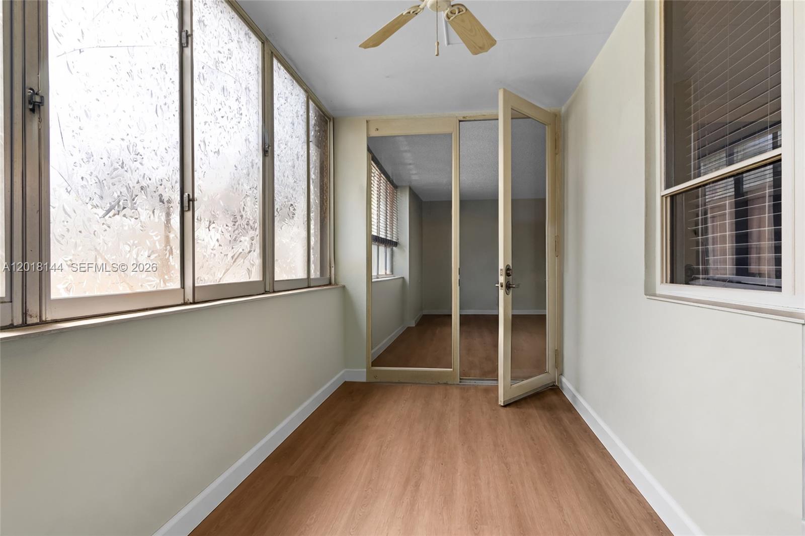 A sunroom with wood-look flooring, large windows, and a glass door leading to another room — 6841 SW 147th Ave # 1D, Miami FL 33193, MIAMI, FL