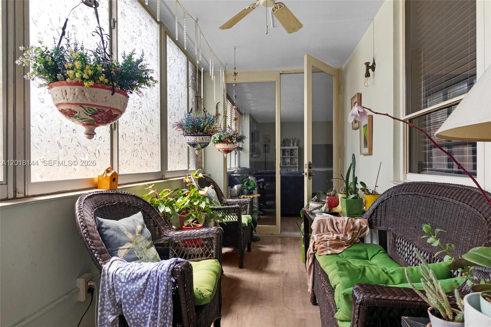 A sunroom features wicker furniture, hanging plants, a ceiling fan, and frosted glass windows — 6841 SW 147th Ave # 1D, Miami FL 33193, MIAMI, FL