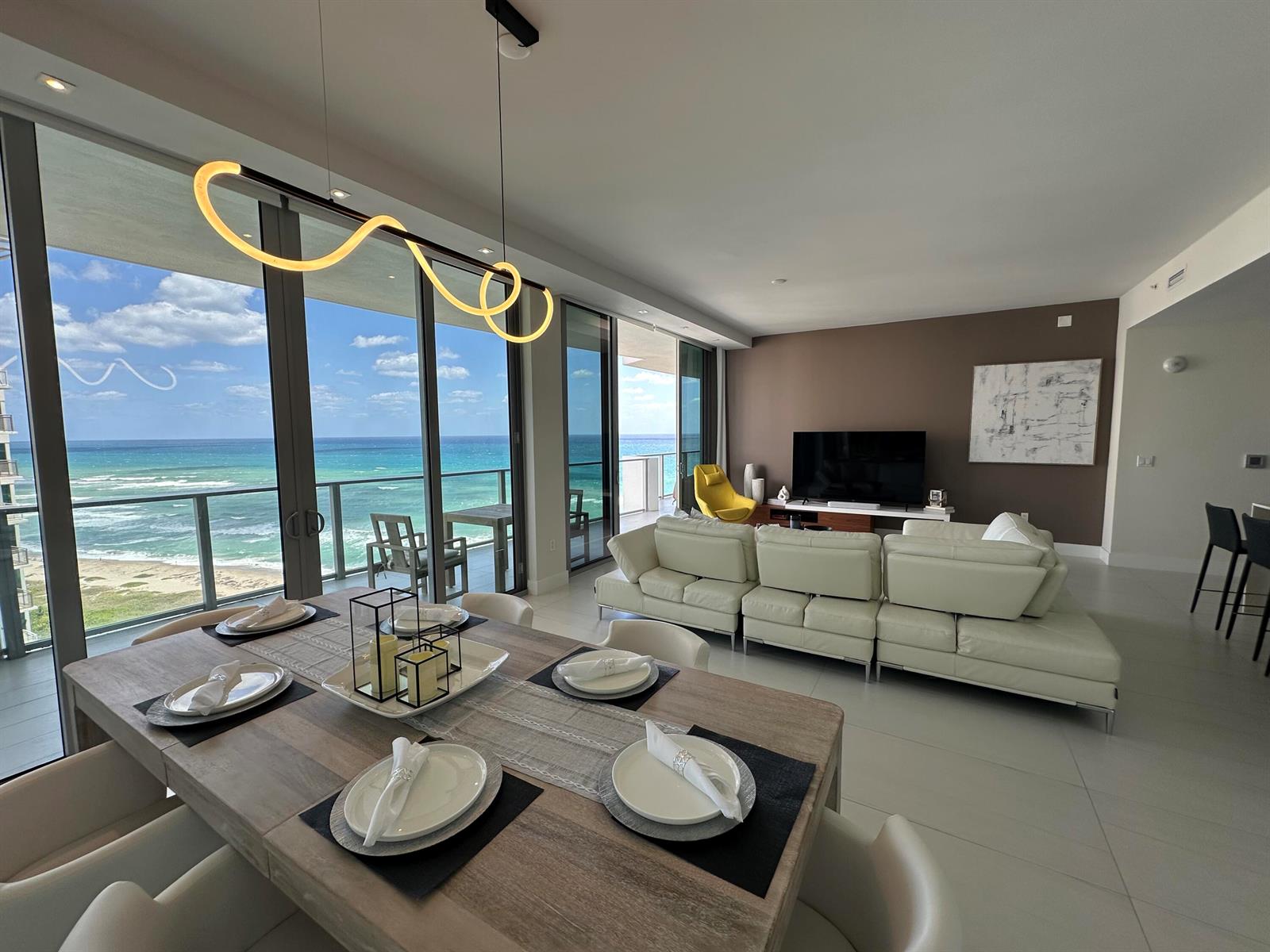 A dining area and living room with ocean views through floor-to-ceiling glass sliding doors — 3100 N Ocean Drive # 1701, Riviera Beach FL 33404, RIVIERA BEACH, FL