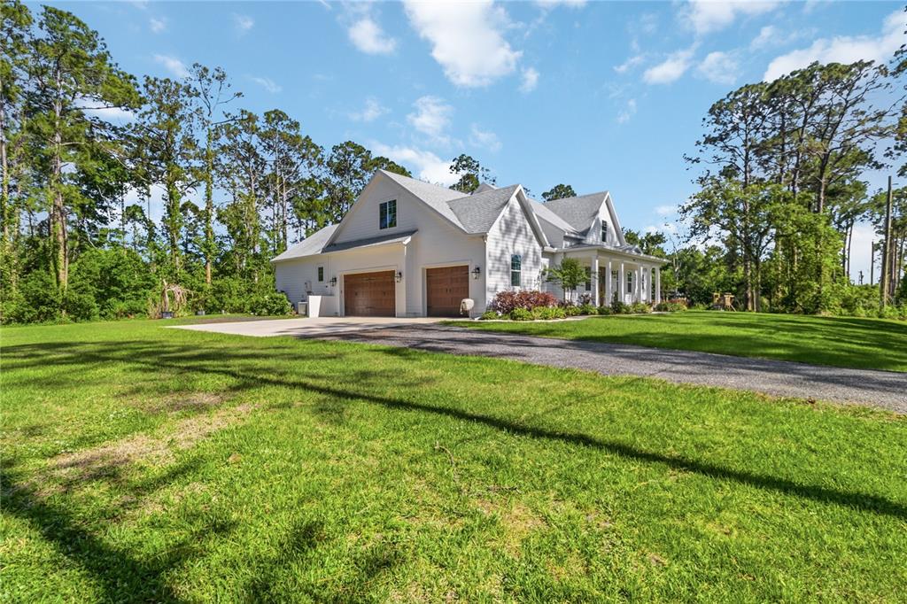 A white house with a gray roof and two wooden garage doors sits on a lawn — 3805 LAKEVIEW ACRES ROAD, ST CLOUD, FL