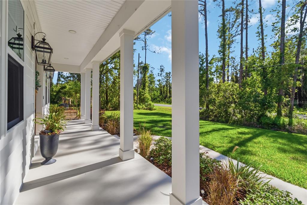 A covered front porch features white columns, hanging lanterns, and a view of the yard — 3805 LAKEVIEW ACRES ROAD, ST CLOUD, FL
