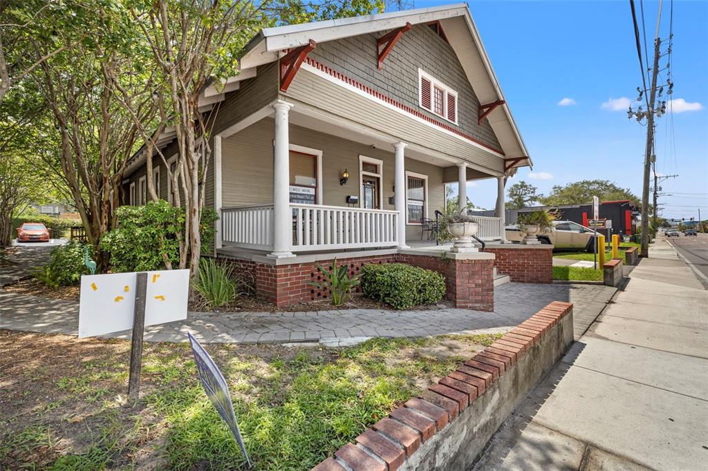 A tan bungalow with a front porch, brick foundation, and a paved walkway — 5135 N FLORIDA AVENUE, TAMPA, FL