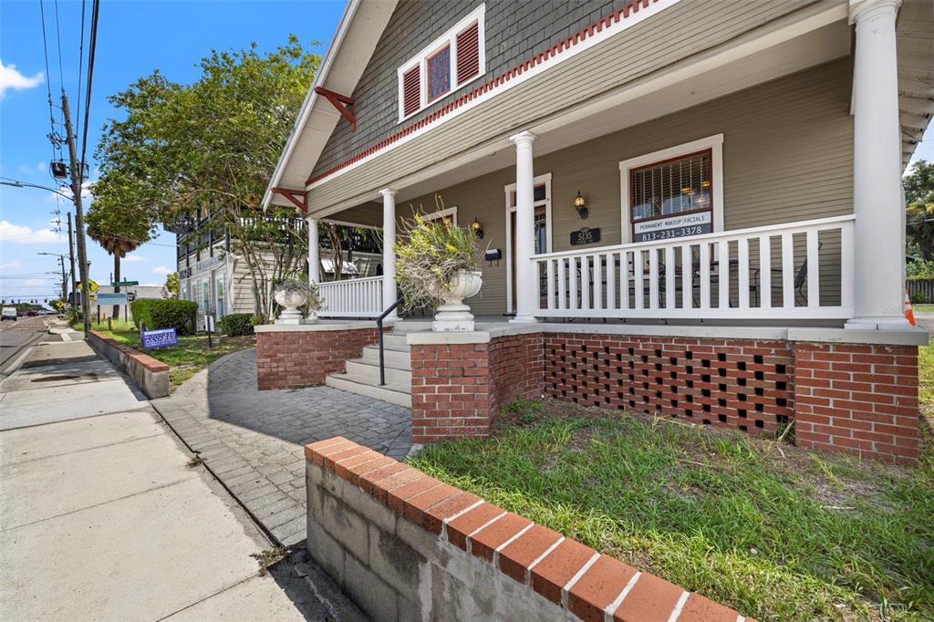A low-angle exterior view of a house with a brick foundation and a front porch — 5135 N FLORIDA AVENUE, TAMPA, FL