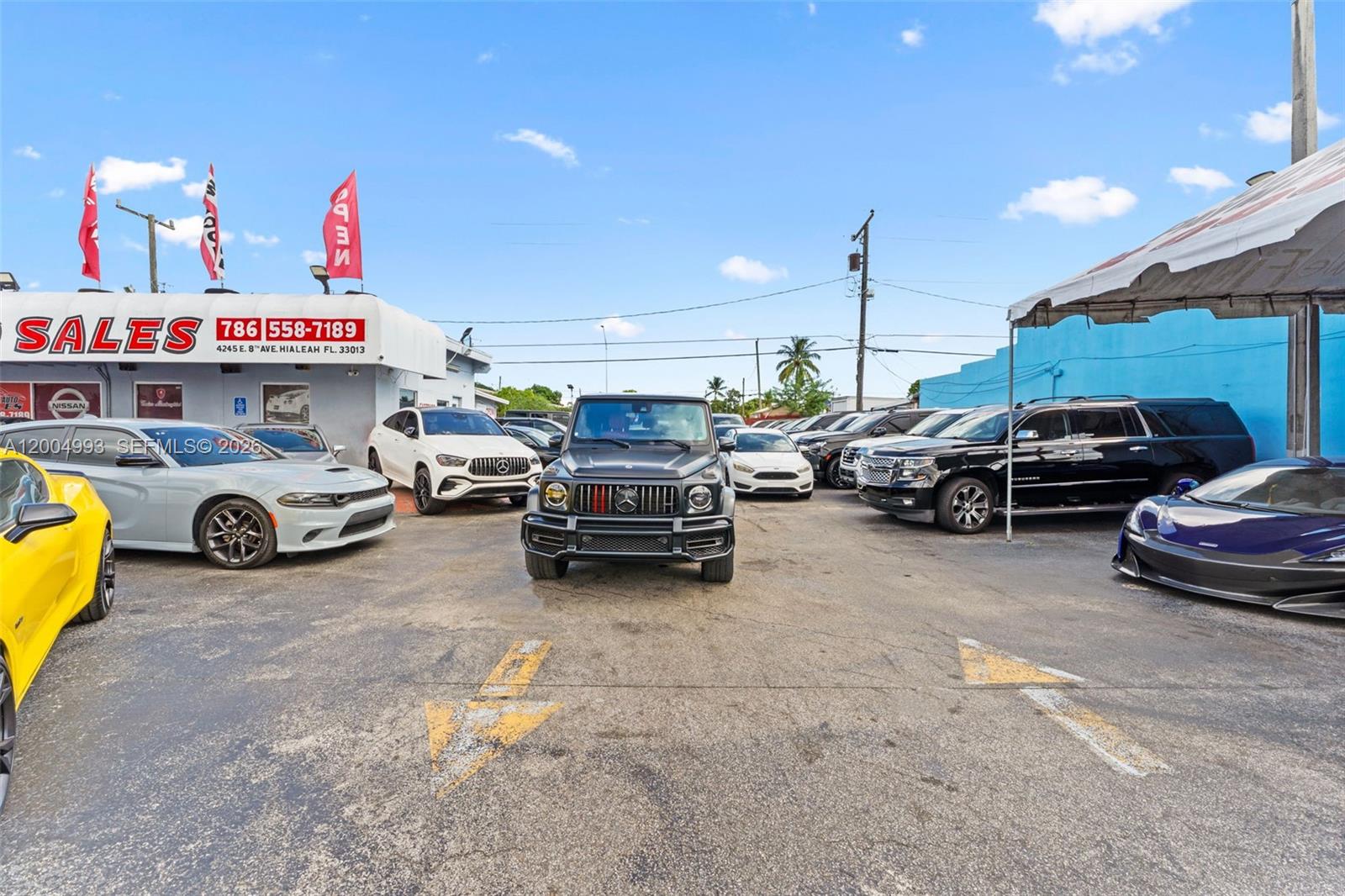 A car dealership lot features a variety of vehicles parked under a bright blue sky — 10301 NW 27th Ave, Miami FL 33147, MIAMI, FL