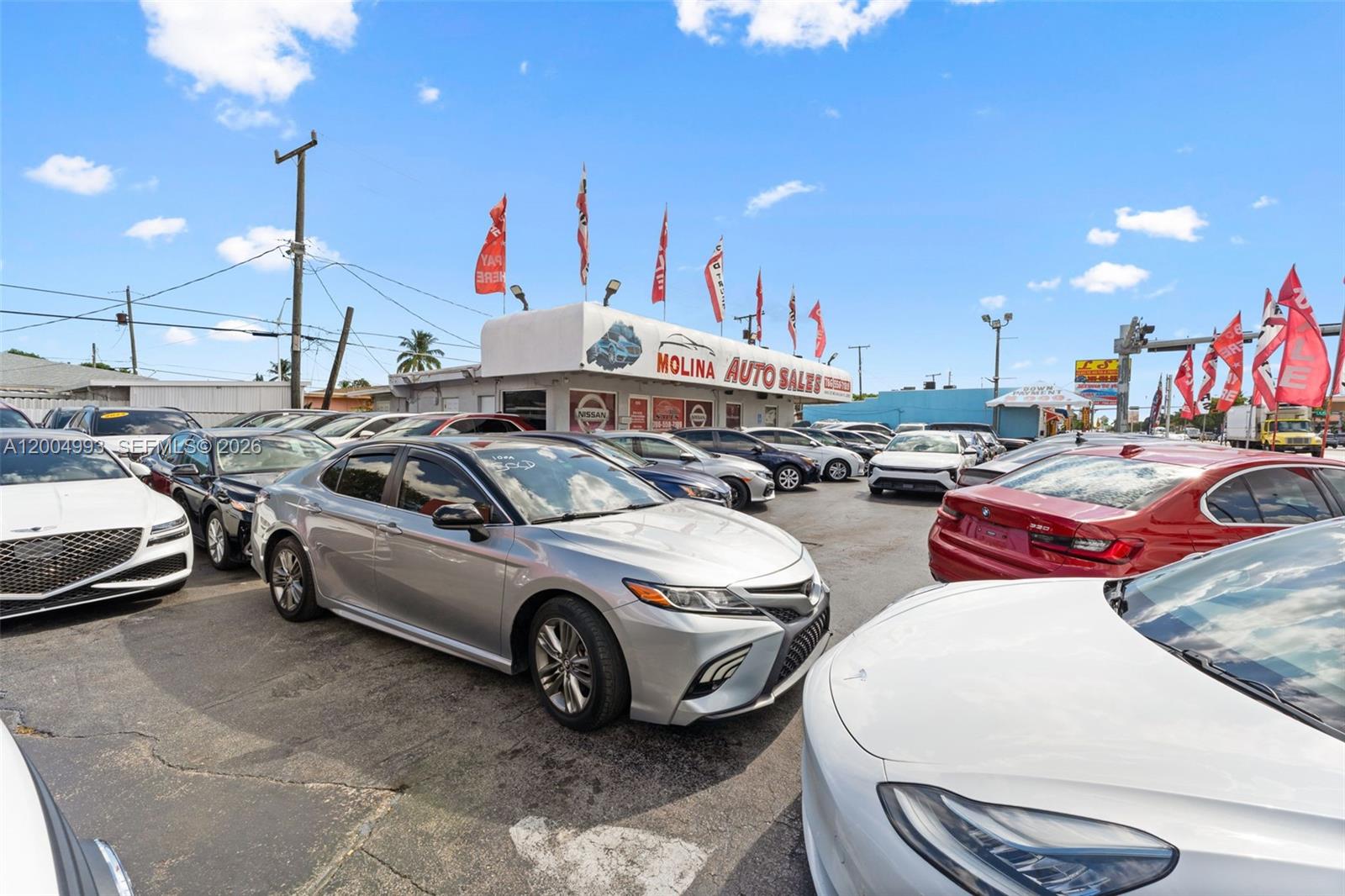 A car dealership lot features numerous vehicles parked in front of a small office building — 10301 NW 27th Ave, Miami FL 33147, MIAMI, FL