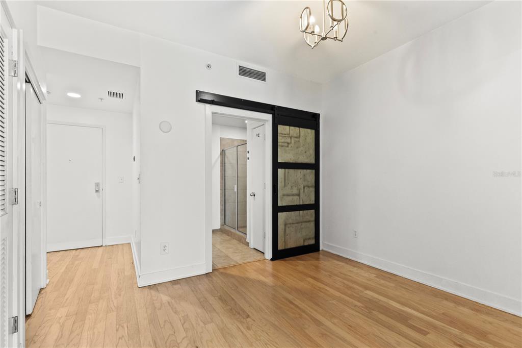 A room with hardwood floors, a sliding barn door, and a view into a bathroom — 1120 E KENNEDY BOULEVARD UNIT 1124, TAMPA, FL