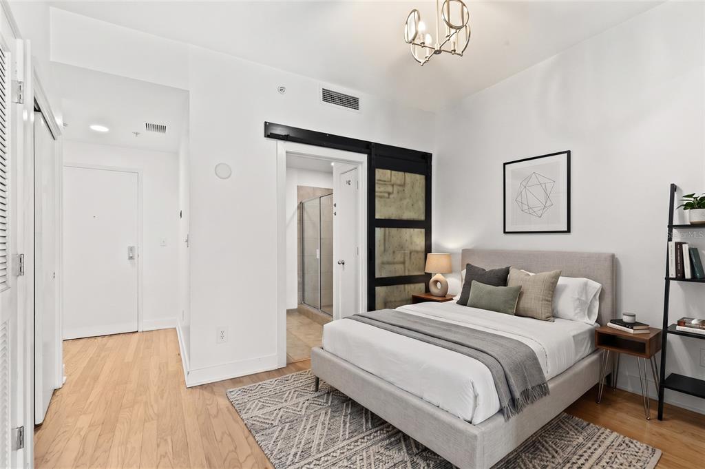 A bedroom features a bed, a sliding barn door to a bathroom, and hardwood floors — 1120 E KENNEDY BOULEVARD UNIT 1124, TAMPA, FL