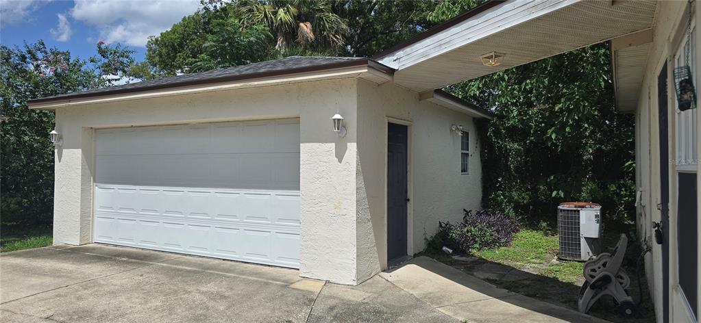 A detached garage with a white door and a covered walkway connecting to the house — 545 CLARK STREET, MAITLAND, FL