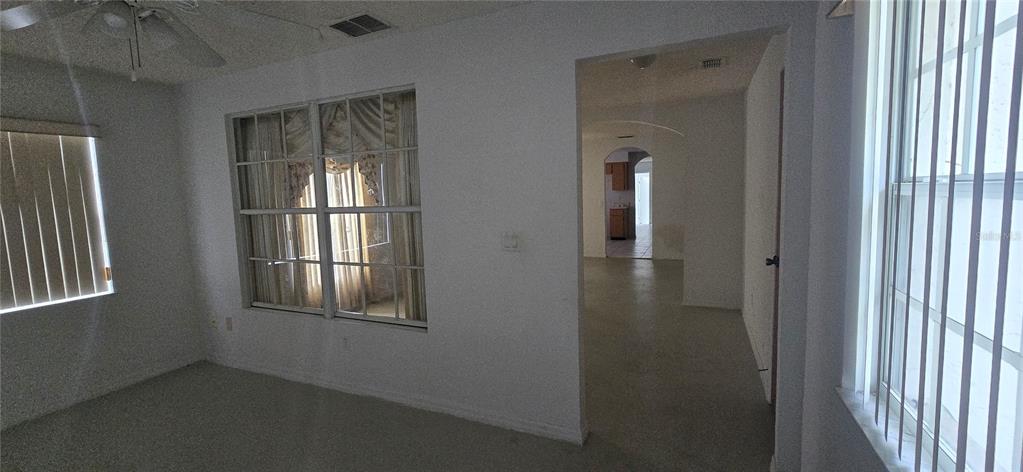 A carpeted room with two windows and a doorway leading to a kitchen area — 545 CLARK STREET, MAITLAND, FL