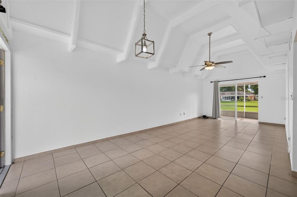 An empty room with a vaulted ceiling, tile flooring, a ceiling fan, and sliding glass doors — 3111 CLUB CIRCLE, LAKE WALES, FL