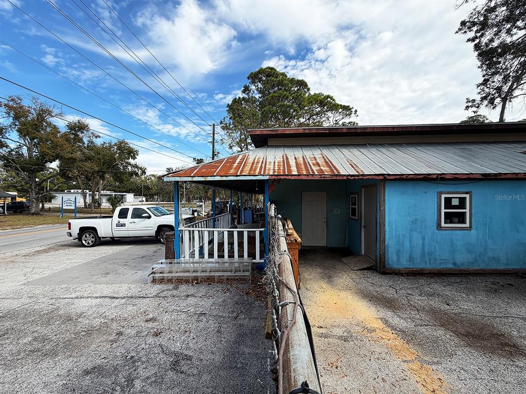 A blue building with a rusted metal roof and a white pickup truck parked nearby — 6028 PINE HILL ROAD, PORT RICHEY, FL