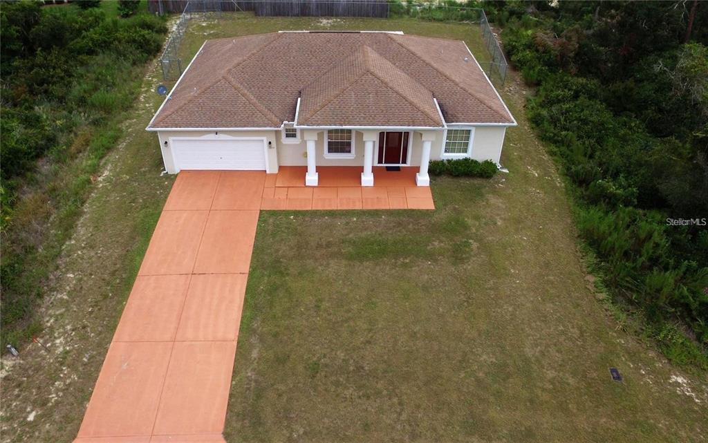 An aerial view shows a single-story house with a brown roof, white siding, and orange driveway — 15747 SW 47TH AVENUE ROAD, OCALA, FL