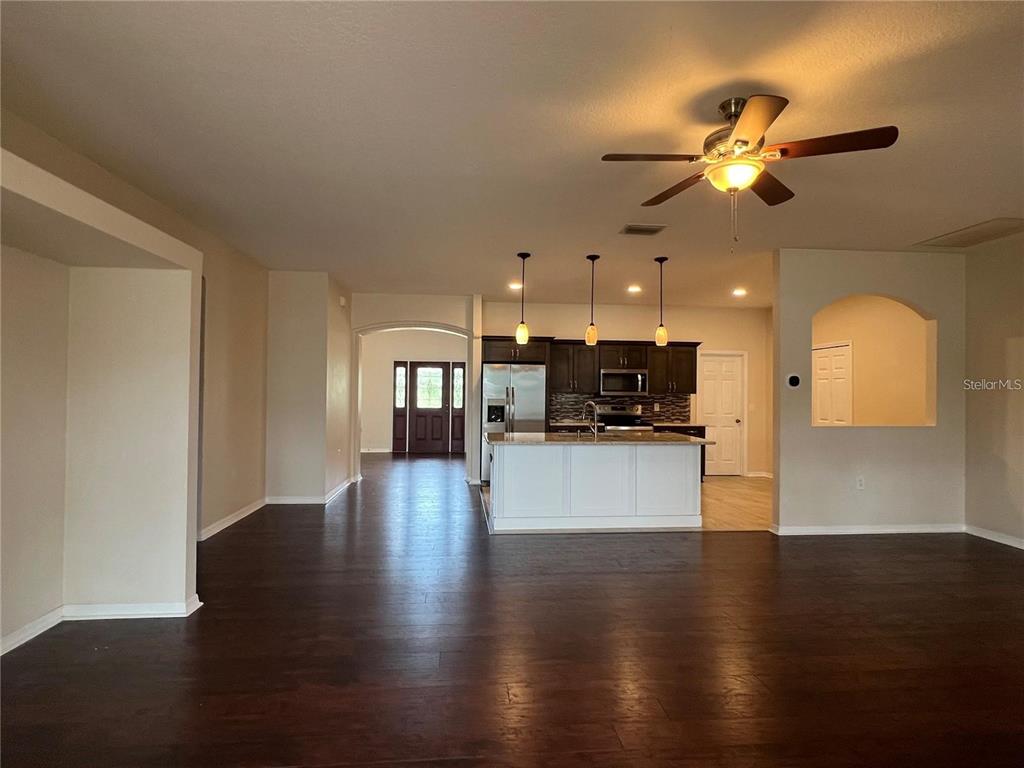 An open-concept living area features dark wood flooring, a kitchen island, and pendant lighting — 15747 SW 47TH AVENUE ROAD, OCALA, FL