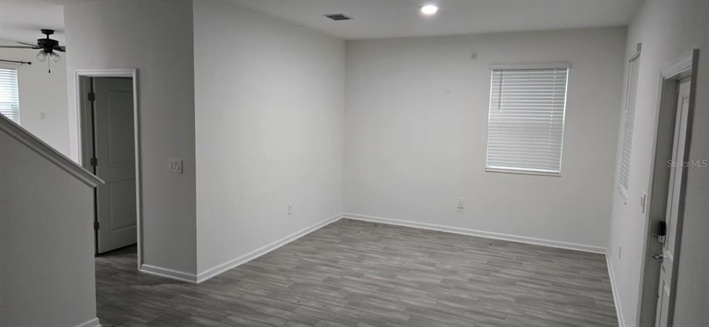 An empty room features light gray wood-look flooring, white walls, and a window with blinds — 13926 TITLE WAY, WINTER GARDEN, FL