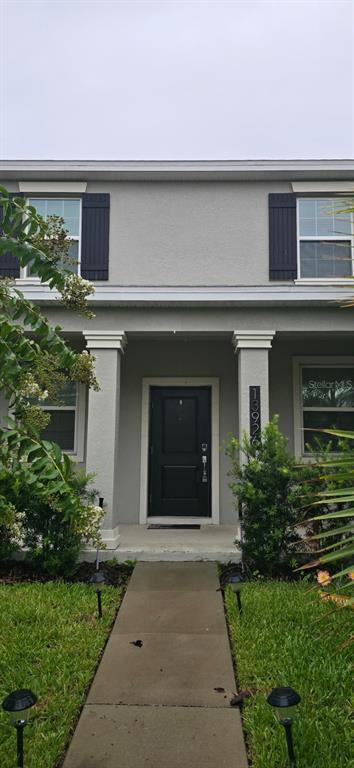 A two-story house exterior features a covered front porch, a black door, and gray siding — 13926 TITLE WAY, WINTER GARDEN, FL