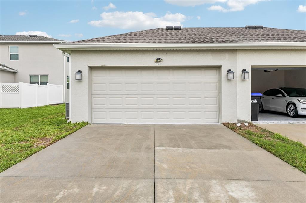 A beige stucco house exterior featuring a two-car garage and a concrete driveway — 13926 TITLE WAY, WINTER GARDEN, FL