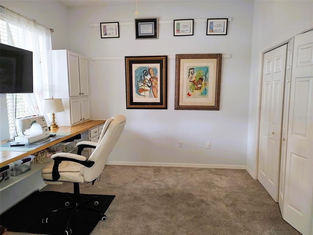 A home office features a built-in desk, a white chair, and framed art on the wall — 3639 HURSTON STREET, NEW PORT RICHEY, FL