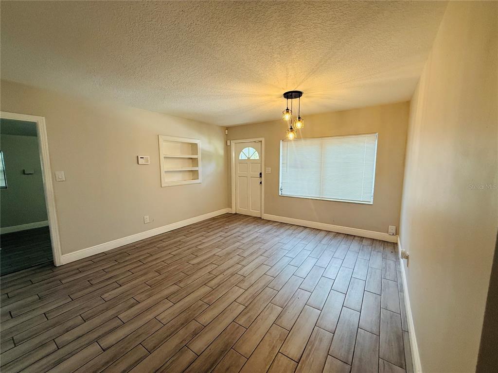 An empty room features light-colored walls, wood-look tile flooring, a built-in shelf, and a pendant light — 4203 E YUKON STREET, TAMPA, FL